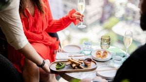woman holding a drink, food on a table, waiter serving her